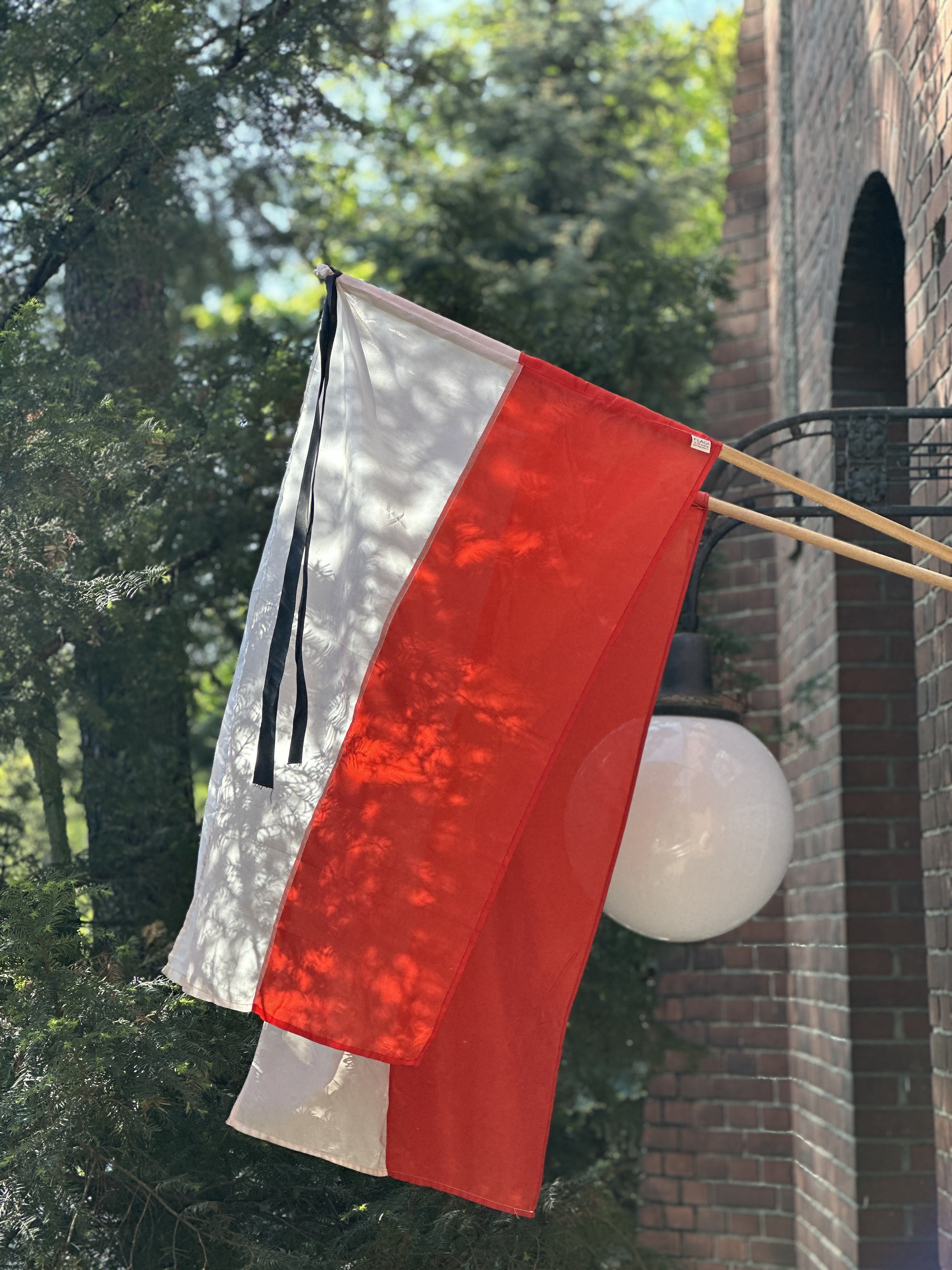 Photo of a Polish flaga with black ribbon attached to it